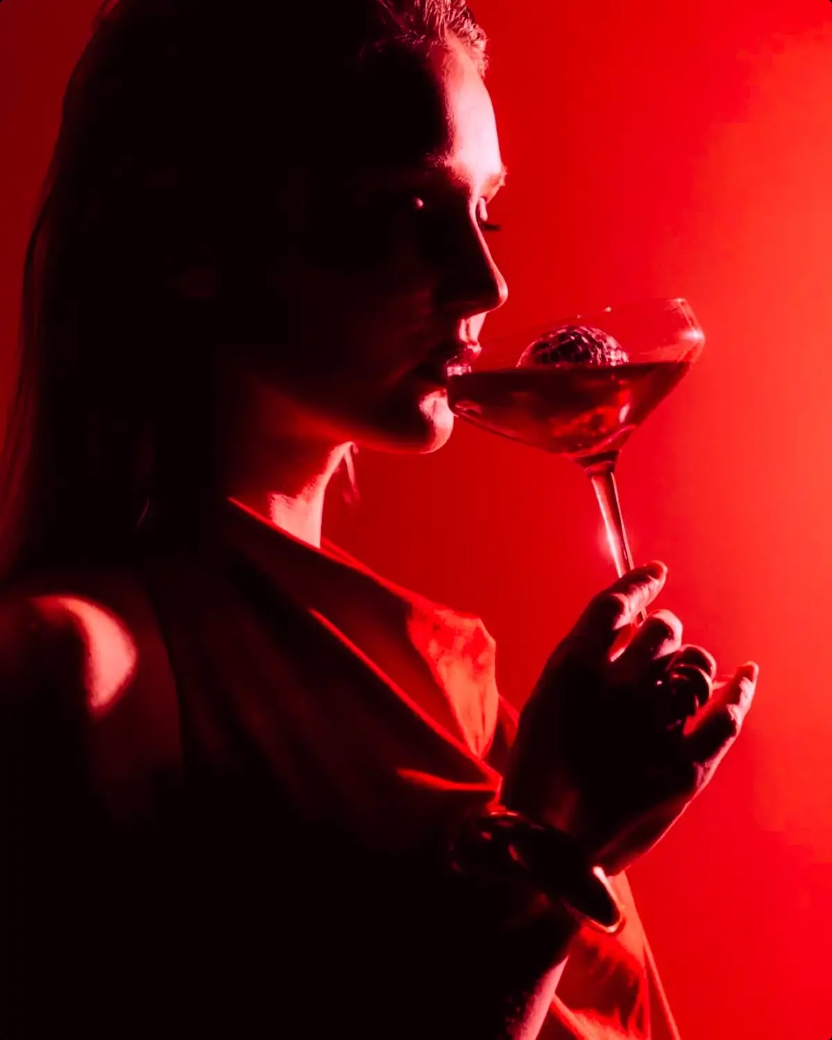 Guest enjoying a signature cocktail under red ambient lighting at AKA Lounge